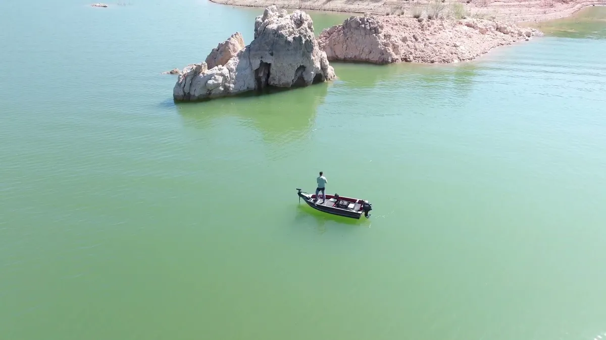 Plano aéreo de una barca en un embalse de aguas turquesas