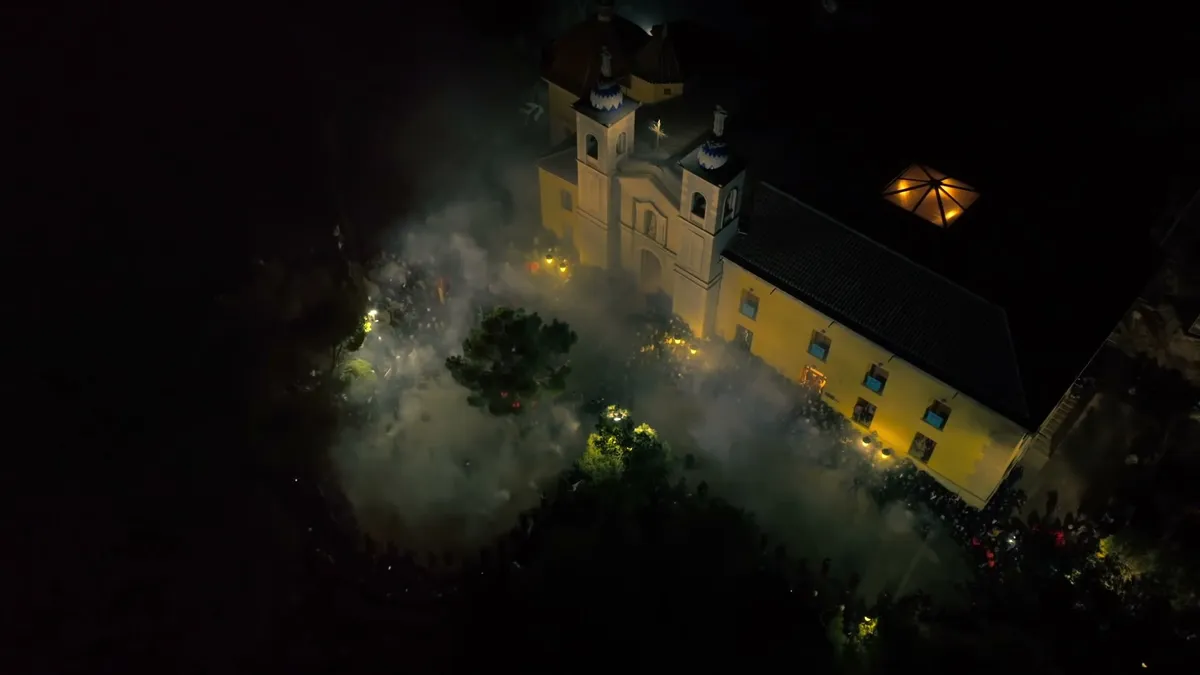Plano aéreo nocturno de una iglesia iluminada entre la niebla